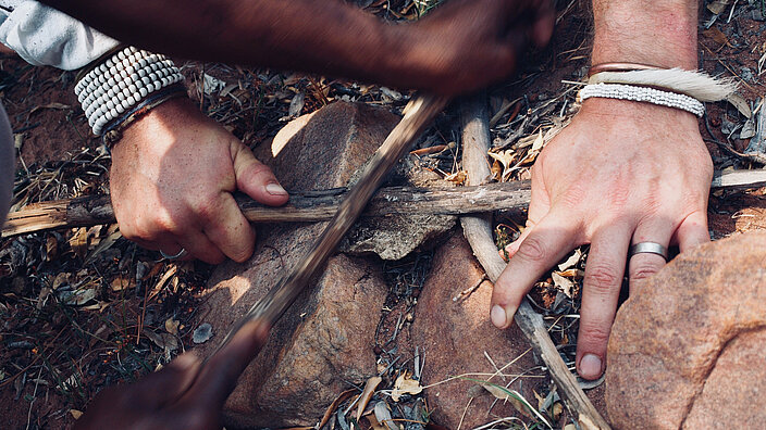 Hands of two persons working on the ground with sticks